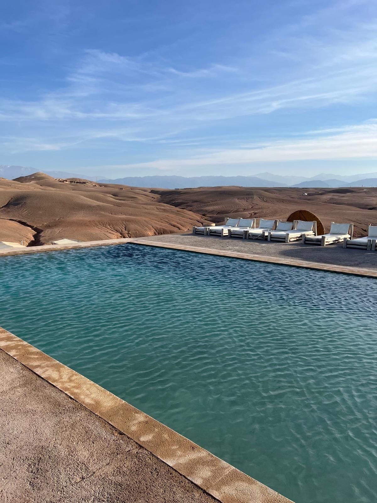 Piscine du camp Al Kamar dans le désert d'Agafay, transats face aux dunes