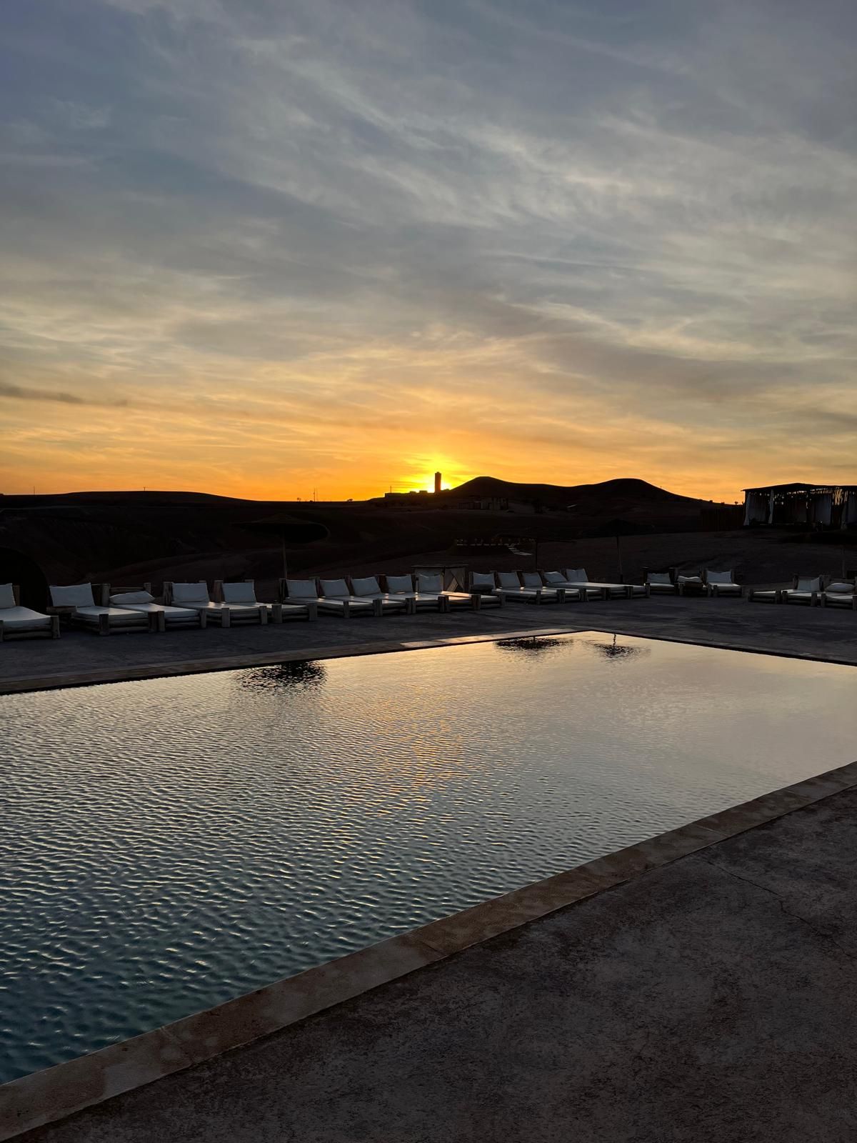 Coucher de soleil sur la piscine du camp Al Kamar dans le désert d'Agafay, près de Marrakech